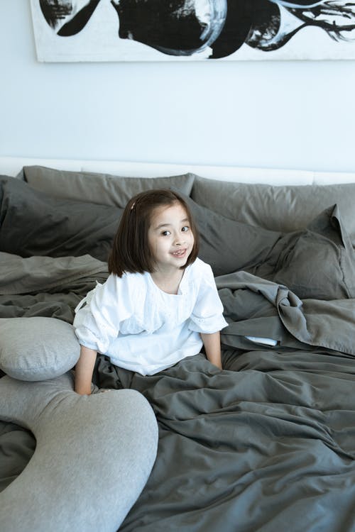 白衬衫和灰色的裤子，坐在灰色的沙发上的女孩 · 免费素材图片