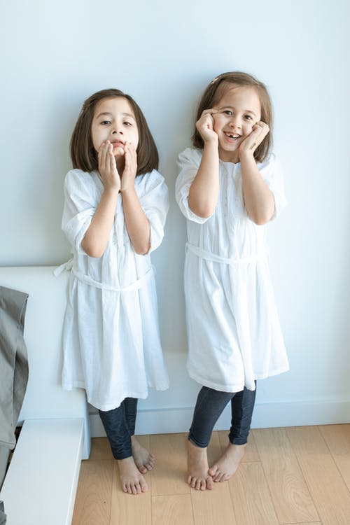 站在灰色的沙发上的白色长袖衬衫和蓝色牛仔牛仔裤的女孩 · 免费素材图片