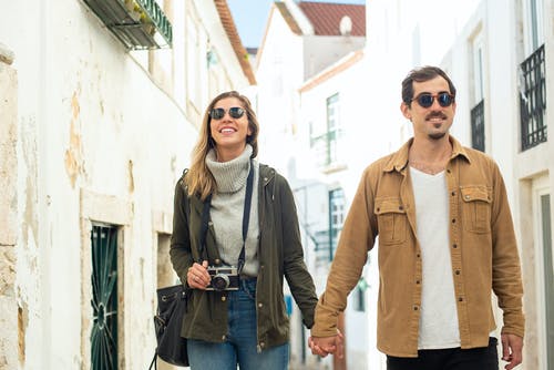 站在白墙上的棕色夹克的女人 · 免费素材图片