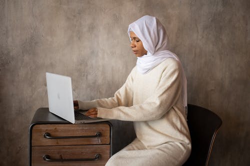 白头巾的女人坐在棕色木制抽屉上 · 免费素材图片
