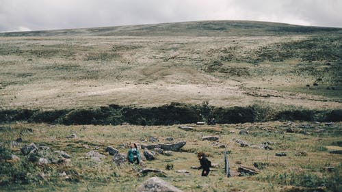 灰色多云的天空下布朗场上的人 · 免费素材图片