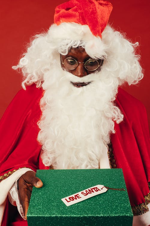 圣诞老人服装的人看起来在圣诞节礼物感到惊讶 · 免费素材图片