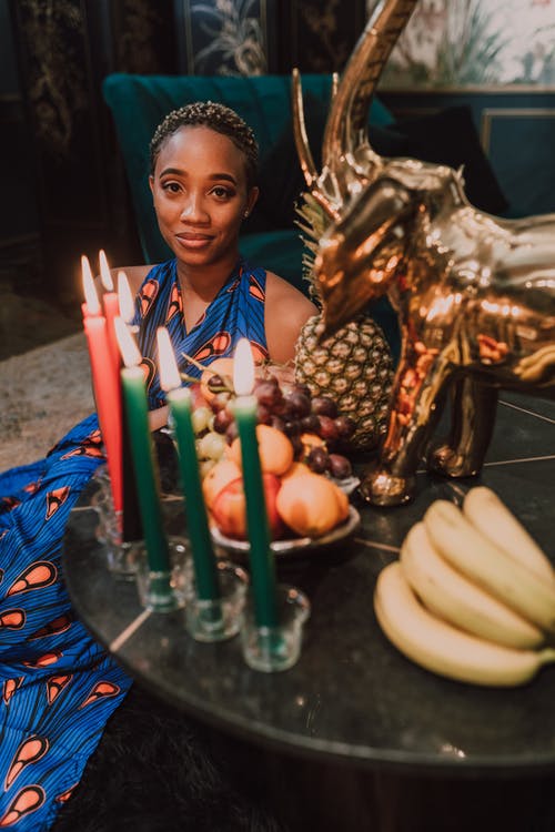 女人坐在桌旁用水果和蜡烛 · 免费素材图片