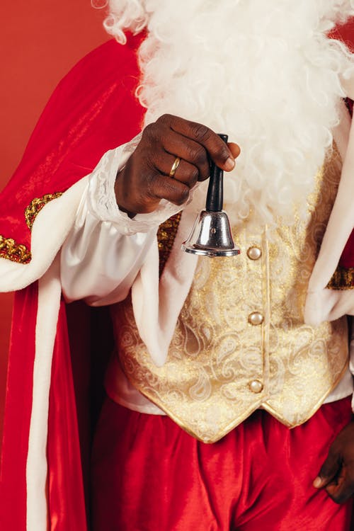 拿着铃铛穿圣诞老人衣服的人 · 免费素材图片
