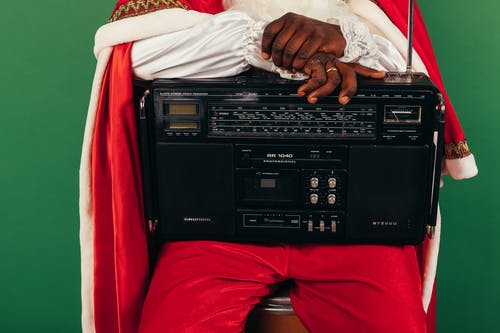 圣诞老人衣服与收音机在他膝上的男人 · 免费素材图片