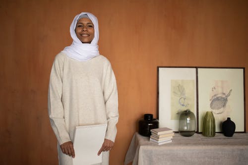 站在棕色木墙附近的白色头巾的女人 · 免费素材图片