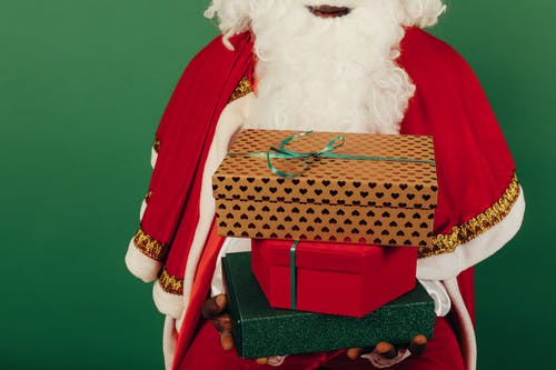 拿着圣诞礼物的时候穿圣诞老人衣服的人 · 免费素材图片