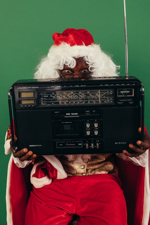 圣诞老人衣服的人拿着一台黑色经典收音机 · 免费素材图片