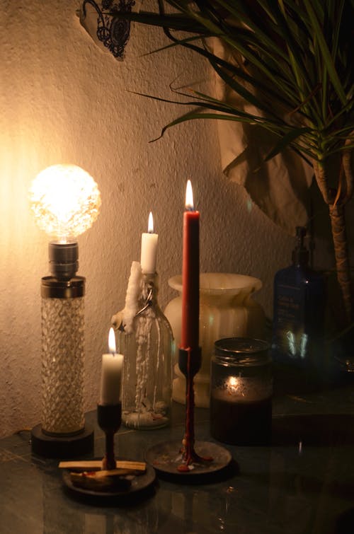 黑色玻璃瓶旁边的白色支柱蜡烛 · 免费素材图片