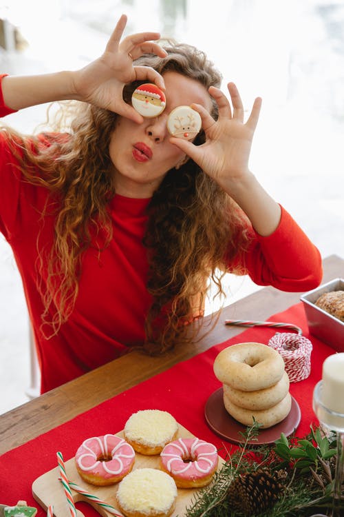 红色的长袖衬衫，拿着白色和棕色甜甜圈的女人 · 免费素材图片