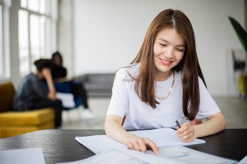 白船员的脖子长袖衬衫握笔写在白纸上的女人 · 免费素材图片