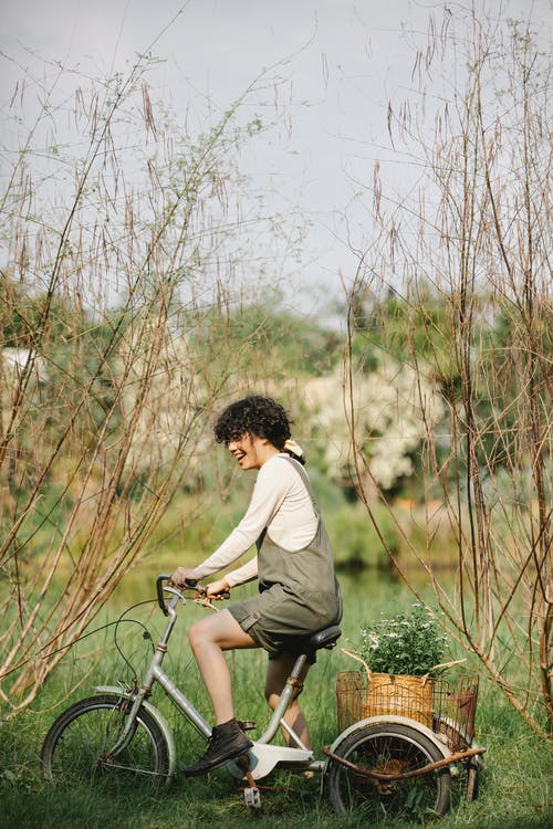 在绿草地上的白色长袖衬衫骑自行车的人 · 免费素材图片