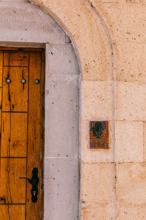 白色的混凝土墙上的棕色木门 · 免费素材图片