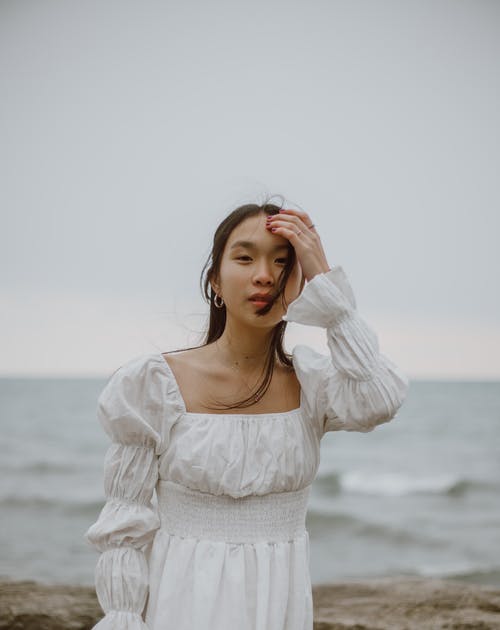 站在海滩上的白色长袖衬衫的女人 · 免费素材图片