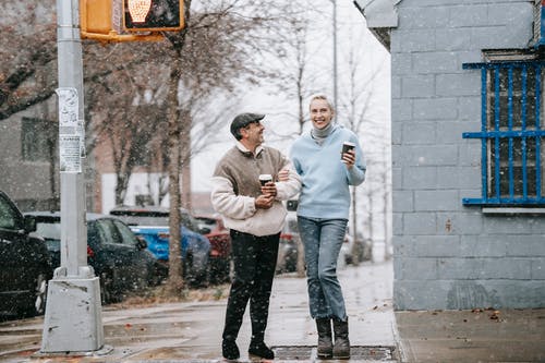 白色连帽衫和黑色裤子站在人行道上的男人 · 免费素材图片