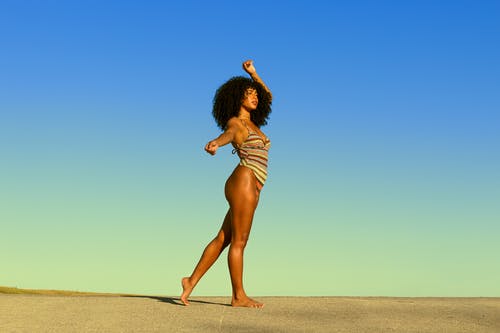 站在棕色沙滩上的白色和黑色条纹衬衫的女人 · 免费素材图片