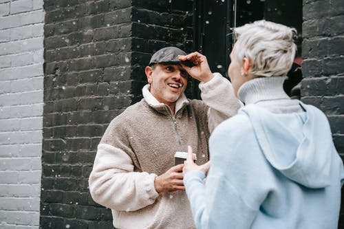 站在棕色砖墙旁边的灰色毛衣的男人 · 免费素材图片