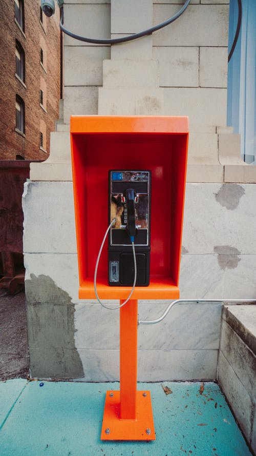 灰色混凝土墙附近的红色电话亭 · 免费素材图片
