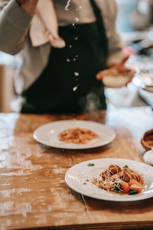 黑色长袖衬衫站在棕色的木桌，白色陶瓷板旁边的女人 · 免费素材图片
