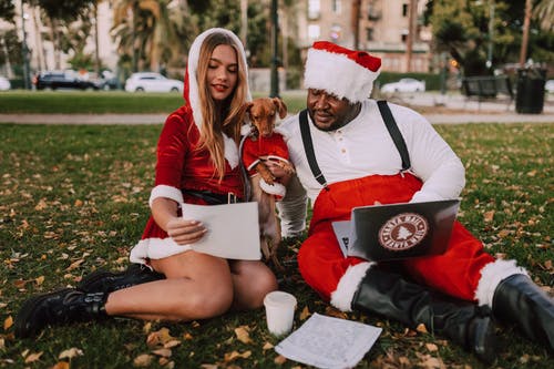 人和狗在圣诞老人服装坐在公园里 · 免费素材图片