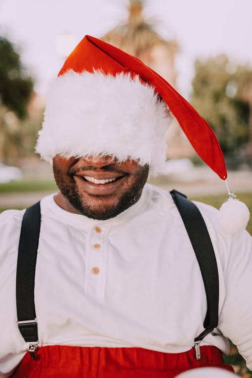 戴着圣诞老人的帽子遮住他的脸的男人 · 免费素材图片