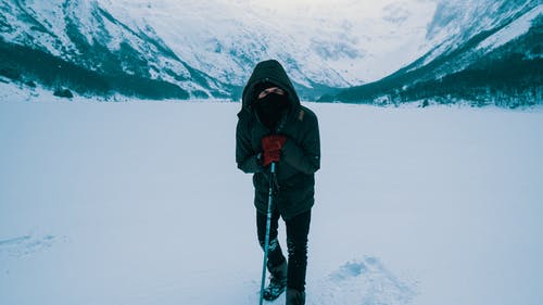 黑色外套和黑色的裤子，站在积雪的地面上的男人 · 免费素材图片