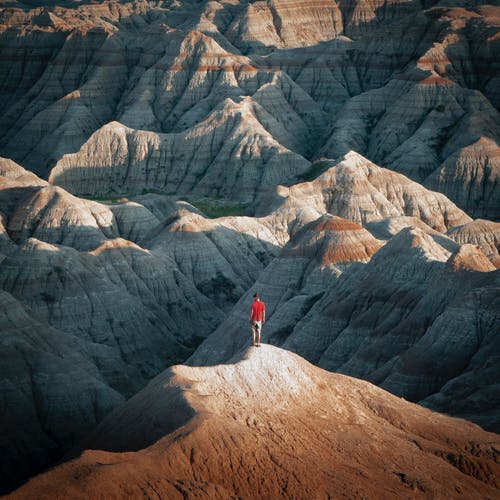 站在棕色的岩石山上的红衬衫的人 · 免费素材图片