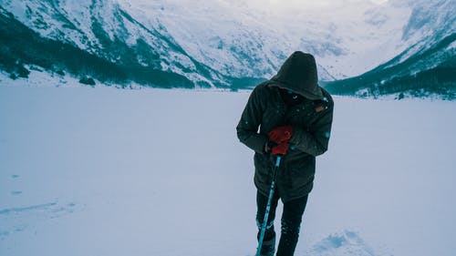 黑色外套和黑色的裤子，站在积雪的地面上的男人 · 免费素材图片