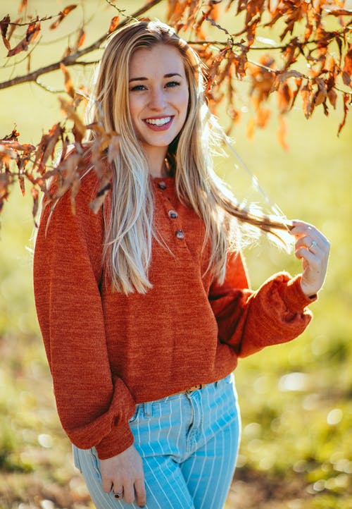 红色毛衣和蓝色牛仔短裤微笑的女人 · 免费素材图片