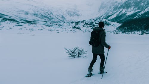 黑色外套和黑色的裤子，站在积雪的地面上的男人 · 免费素材图片