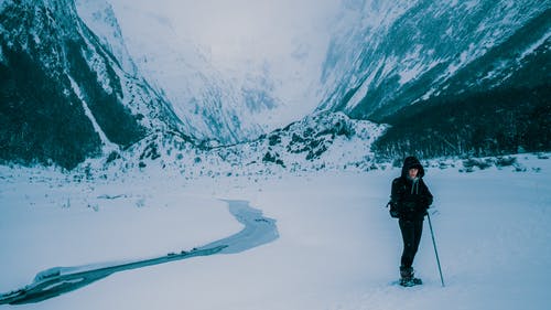 黑夹克和裤子站在积雪的地面上的男人 · 免费素材图片