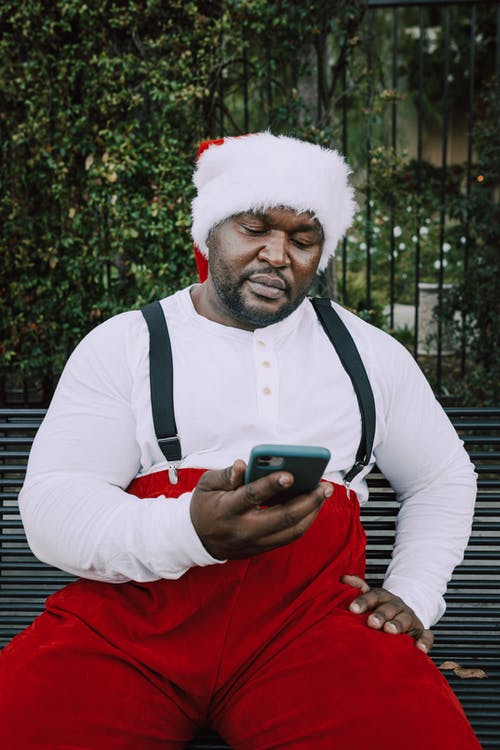圣诞老人衣服的人看他的智能手机 · 免费素材图片