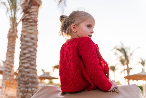 坐在白色纺织上的红色毛衣的女孩 · 免费素材图片