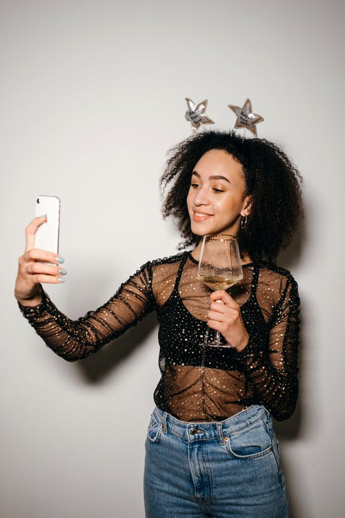 拿着白色iphone 5 C的黑色和棕色长袖衬衫的女人 · 免费素材图片