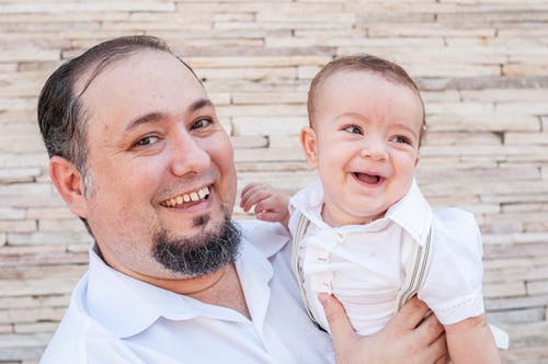 白色礼服衬衫的男人抱着婴儿的白色礼服 · 免费素材图片