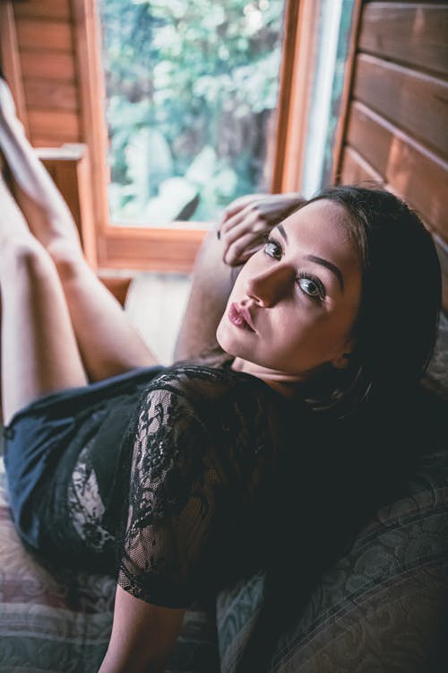 黑色和白色的花衬衫，躺在棕色的木床上的女人 · 免费素材图片