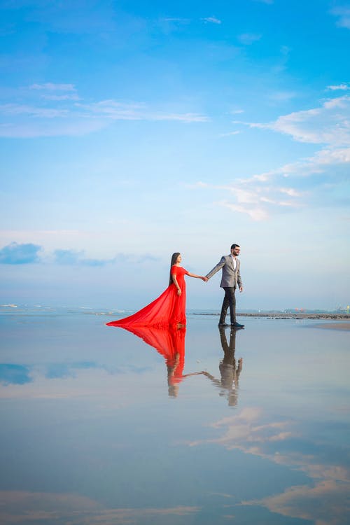 拿着红伞站在海边的白色连衣裙的女人 · 免费素材图片