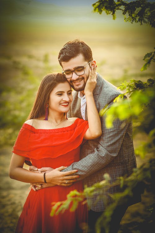 黑色和白色格仔的恤衫的男人拥抱穿着红色衣服的女人 · 免费素材图片