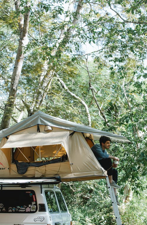 男人和女人坐在被树木包围的帐篷上 · 免费素材图片