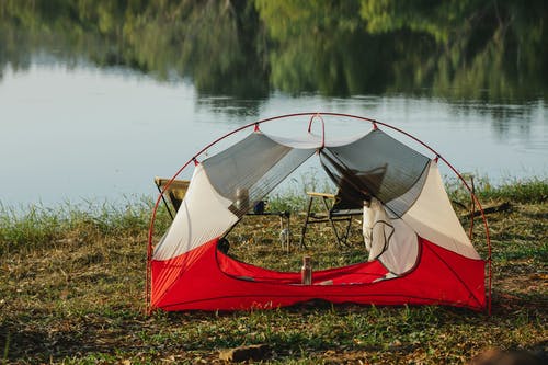 在湖附近的绿草上的红色和白色帐篷 · 免费素材图片