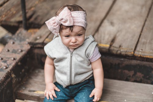 灰色衬衫和蓝色牛仔短裤，坐在棕色木地板上的女孩 · 免费素材图片