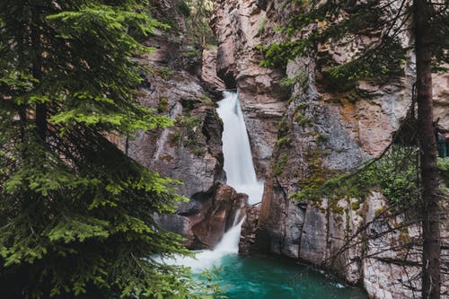 棕色和绿色的洛矶山脉之间的瀑布 · 免费素材图片