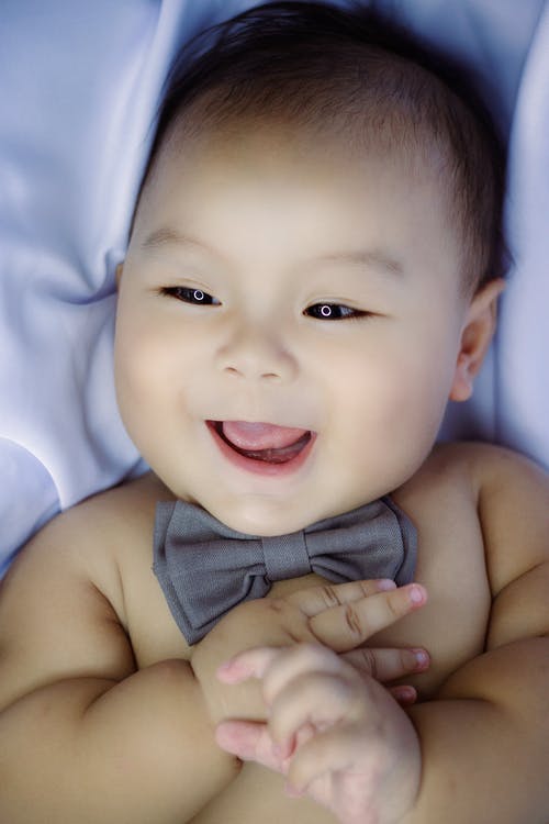 婴儿躺在白色纺织上的黑色和白色的圆点领结 · 免费素材图片