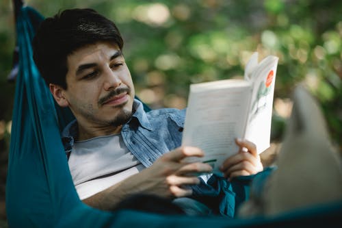 蓝色polo衫阅读书中的男人 · 免费素材图片