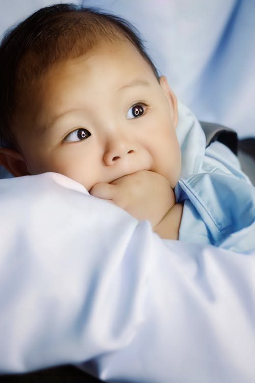 婴儿躺在衬衫上白色纺织的蓝色按钮 · 免费素材图片
