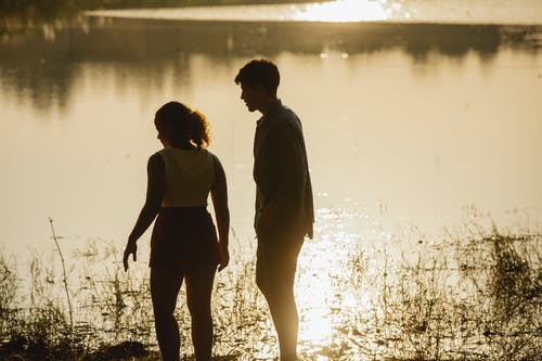 男人和女人站在水体附近的地面上 · 免费素材图片
