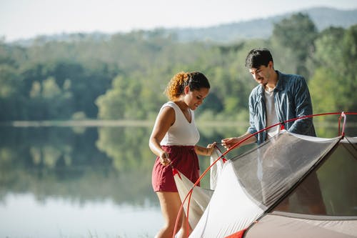男人和女人在湖上举行白色和红色的小船 · 免费素材图片