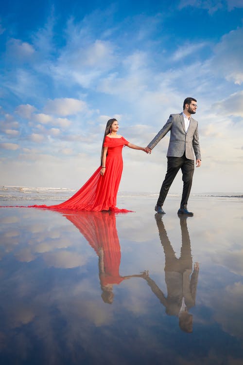 男人和女人在沙滩上散步时手牵着手 · 免费素材图片