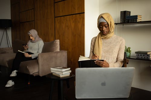 米色头巾的女人坐在灰色的沙发椅子上 · 免费素材图片