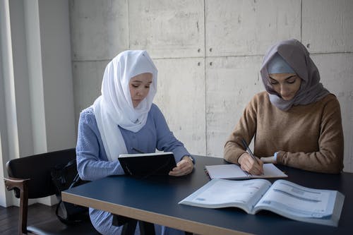 白色头巾和棕色毛衣，使用黑色平板电脑的女人 · 免费素材图片